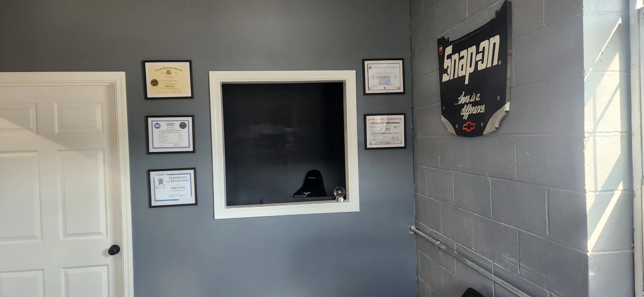 The Stepp's front desk window with automotive training certificates displayed on the wall